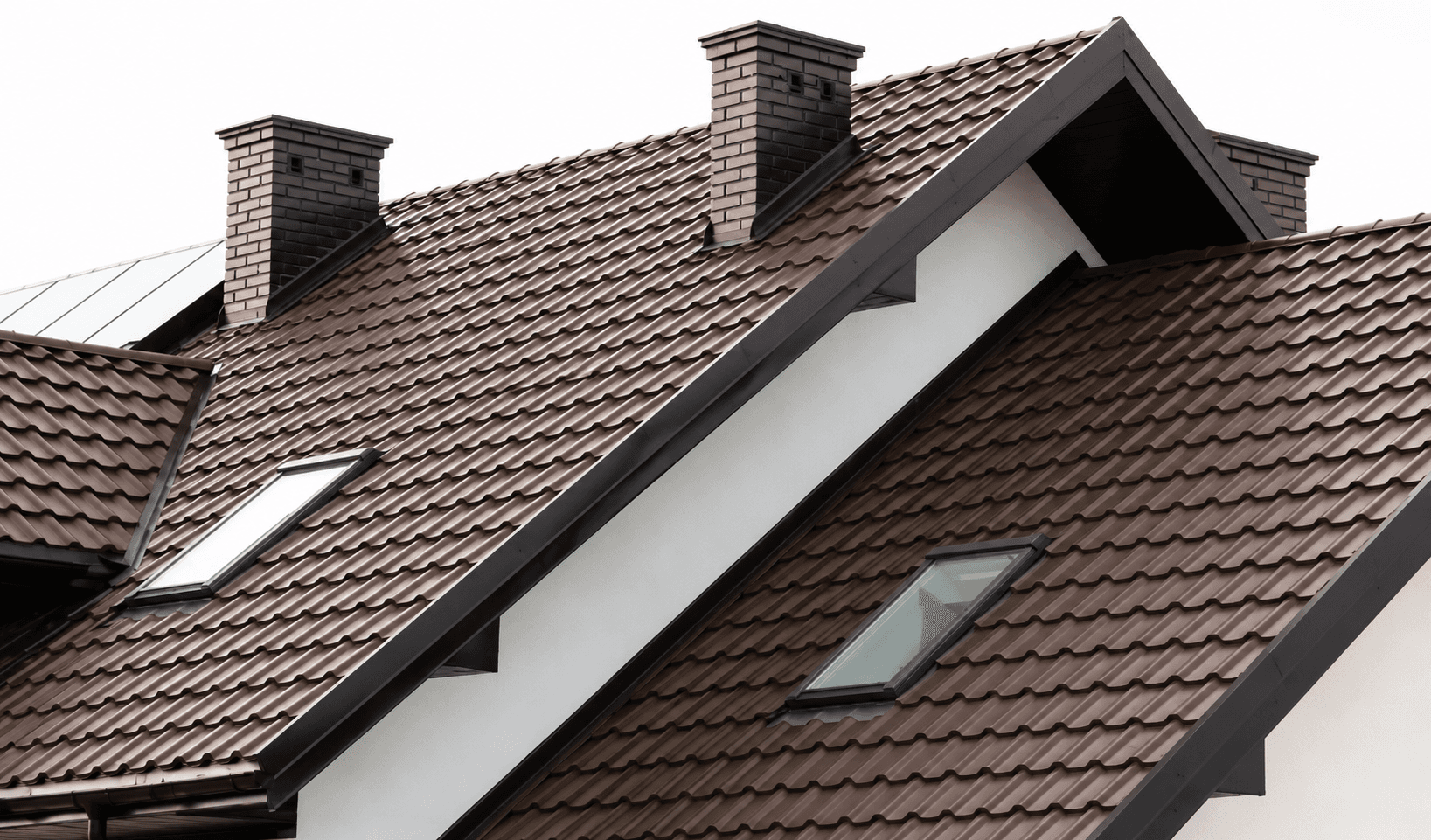 Brown metal tile roof with several gables, a projecting dormer and two roof windows set into the pitch